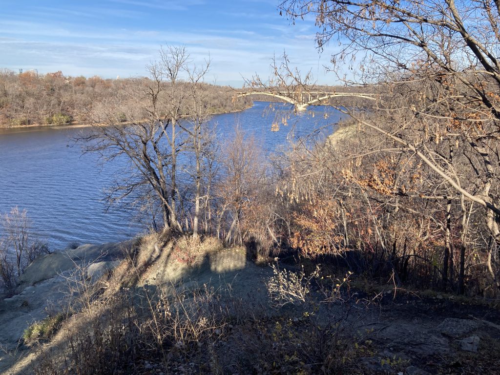 My view from the overlook at the civil war monument. From back to front: sky, lake street bridge, west river bluff, river, bare tree branches, cliff, a shadow of me taking this picture, dirt 